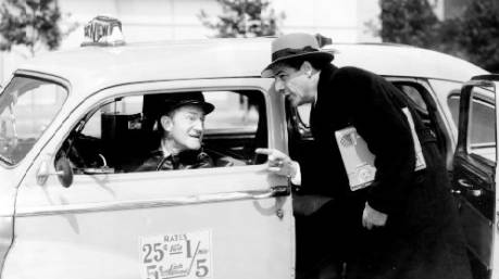 A vintage photo of a man speaking with the driver of a taxicab